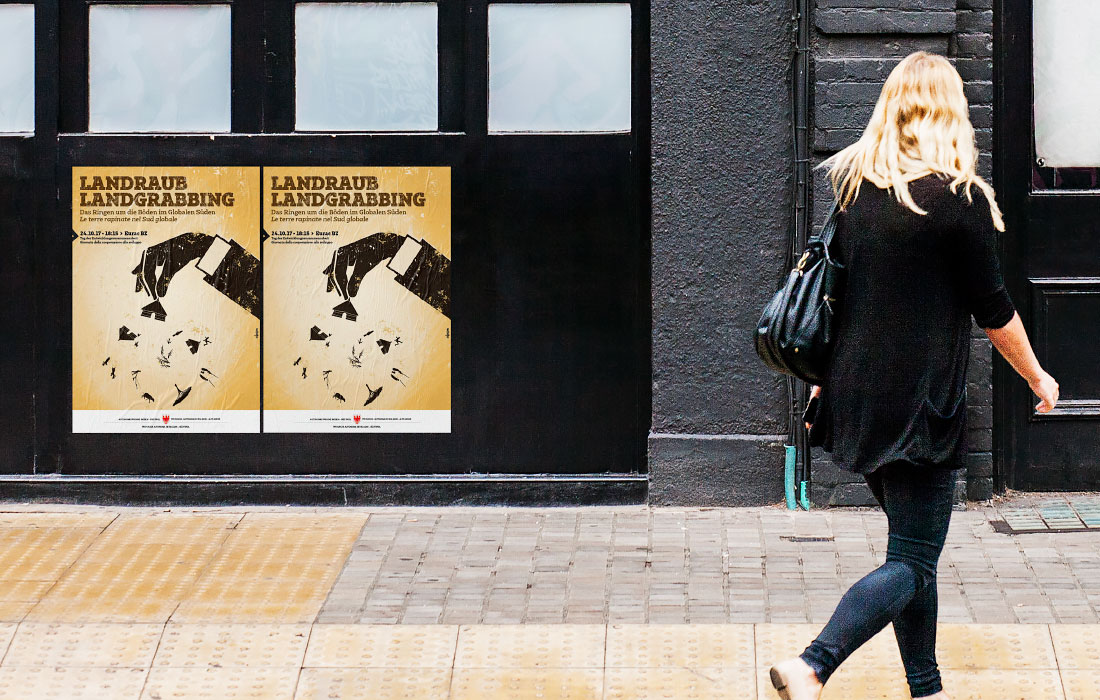 Plakat „Landraub, Land grabbing: Das Ringen um die Böden im Globalen Süden“ im urbanen Umfeld. Ein ökosozialer Poster in Südtirol, Bozen. Grafik von der adpassion Werbeagentur, Waldemar Kerschbaumer.